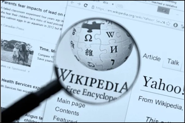 Une loupe zoome sur le symbole de l'encyclop&eacute;die en ligne pour montrer comment ajouter une image sur Wikip&eacute;dia.